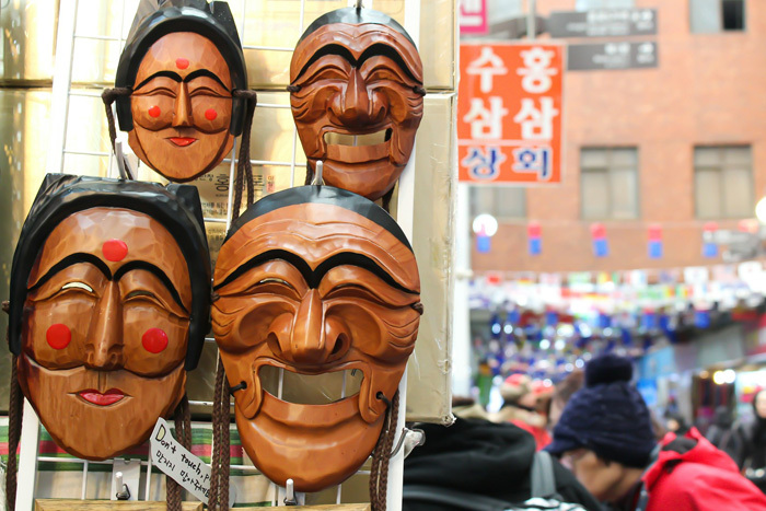 Korean traditional wooden masks hang from a display rack in Gwangjang Market, South Korea.
